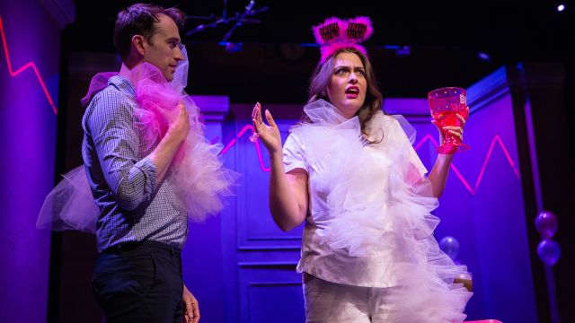 Kiki (Hayley Lovgren) tries to convince Jordan (Kyle Cameron*) to bring Will, the new guy at work, as his plus-one to her wedding.